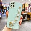 Mint green smartphone case with a decorative gold heart chain attachment.