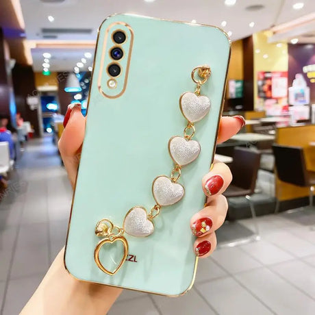 Mint green smartphone case adorned with a decorative chain of pearlescent heart charms.