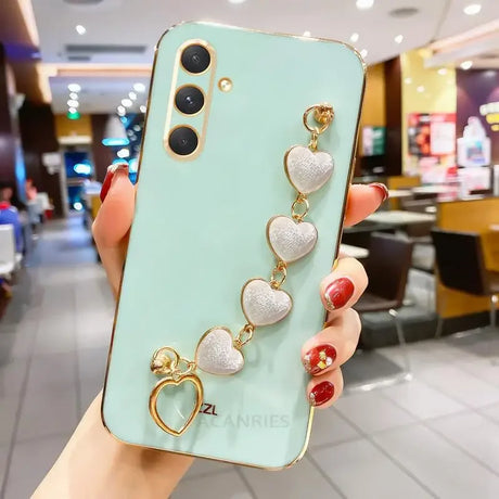 Mint green smartphone with a decorative heart-shaped charm bracelet attached.