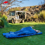 a man sleeping in a sleeping bag next to a jeep