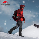 a man in a red jacket and black pants is walking up a snowy hill