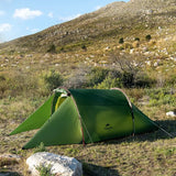 a green tent pitched up on a rocky hillside