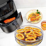 there are onion rings on a plate next to an air fryer