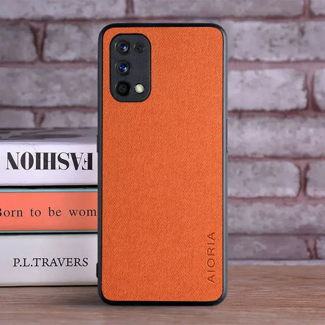 The orange leather iphone case is on a table next to a stack of books