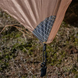 there is a brown and black umbrella hanging from a tree