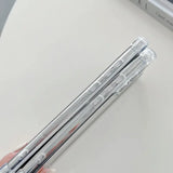 someone holding a pair of silver metal pens on a table