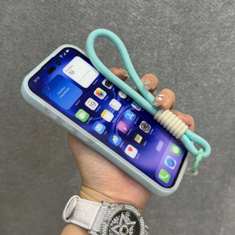 Pale blue iPhone with a screen displaying various apps and a mint green lanyard with a cream-colored bead attached.