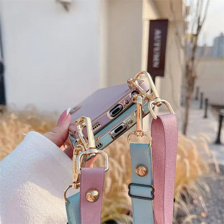 Pastel-colored phone case with attached decorative straps and gold hardware.