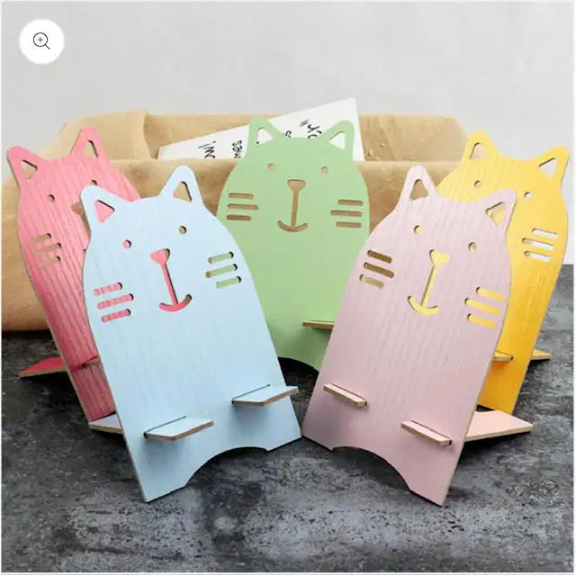 Pastel-colored wooden cat-shaped phone stands in pink, blue, green, and yellow.