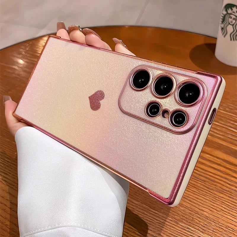 Pearlescent pink and gold gradient smartphone case with a heart accent and prominent camera cutouts.