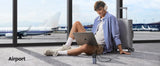 Person sitting on airport floor using a laptop.