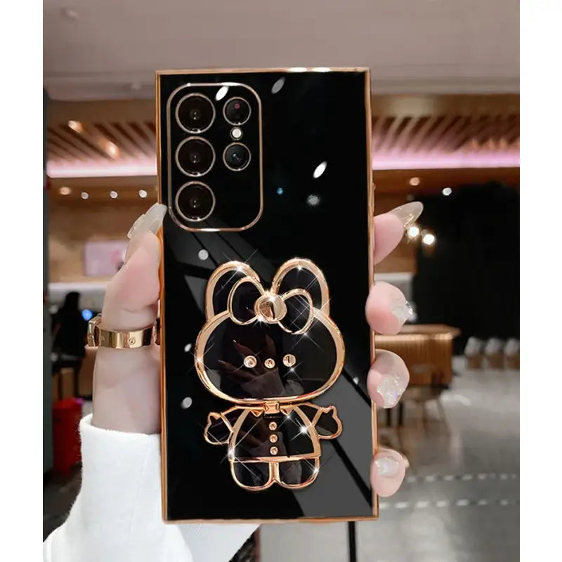 a person holding a black and gold iphone case