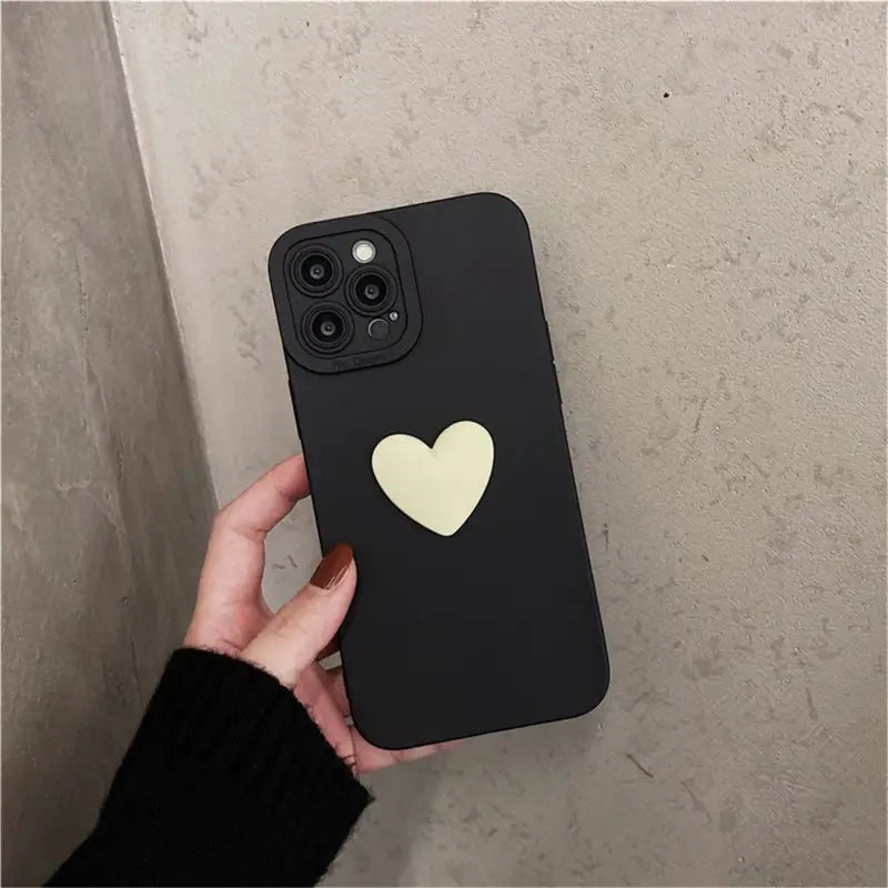 a person holding a black phone case with a heart