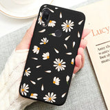 a person holding a black phone case with white daisies on it