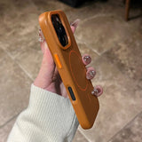 A person holding a brown leather phone case with orange buttons and a circular design.