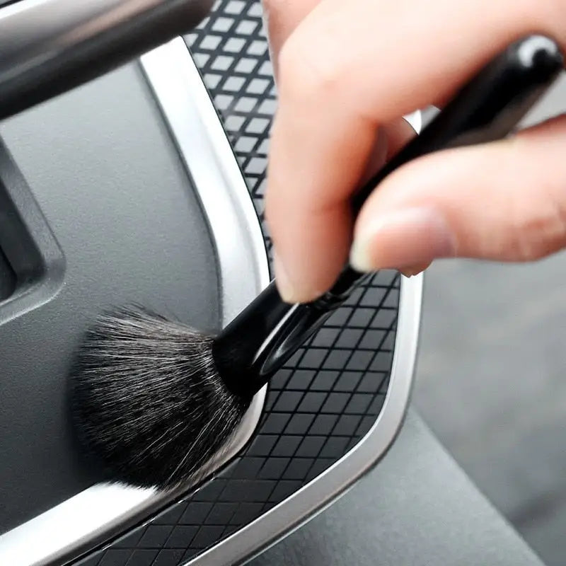 a person using a brush to clean the interior of a car