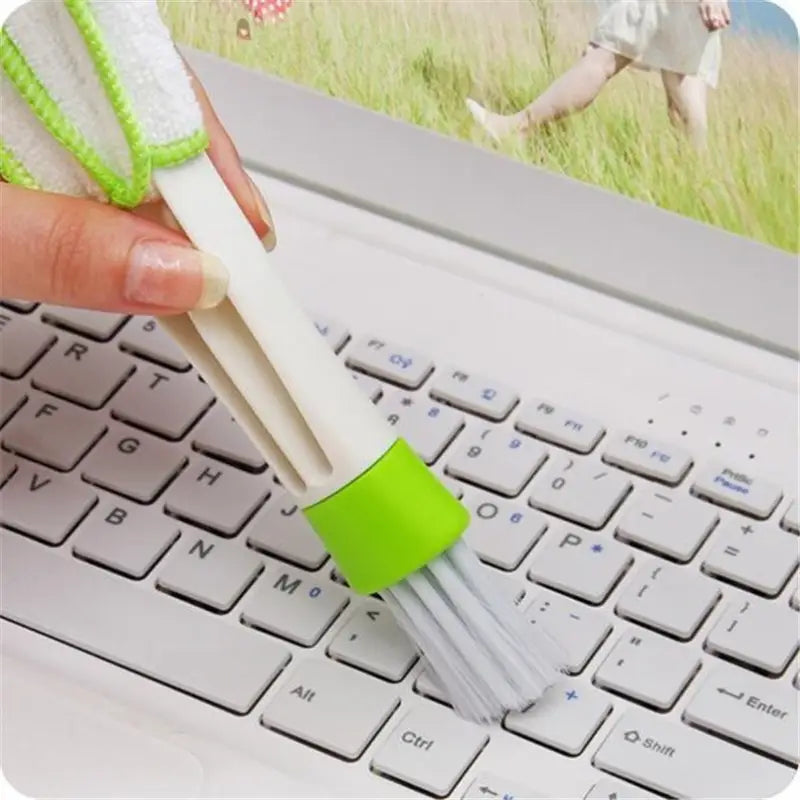 a person using a brush to clean a laptop keyboard