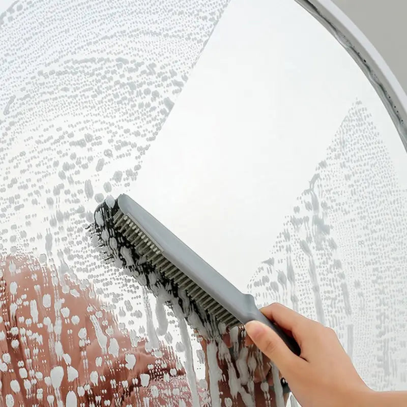 a person using a brush to clean a large circular mirror