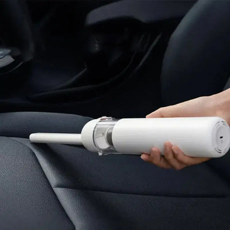 A person using a car vacuum to clean the interior