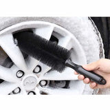 a person cleaning a car wheel with a brush