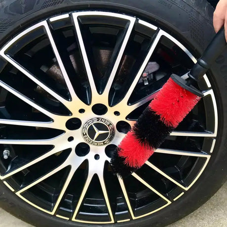 a person cleaning a car wheel with a brush