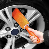a person cleaning a car wheel with a brush