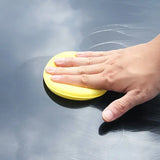 a person’s hand is cleaning a car with a sponge