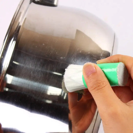 a person is cleaning a metal cup with a brush