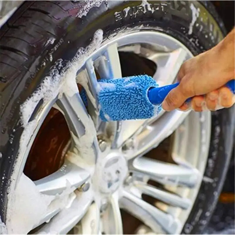 a person cleaning a car tire with a sponge