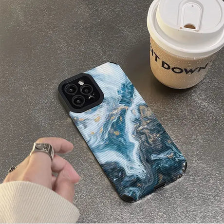 A person holding a coffee cup and a phone case