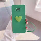 A person holding a green phone case with a heart on it