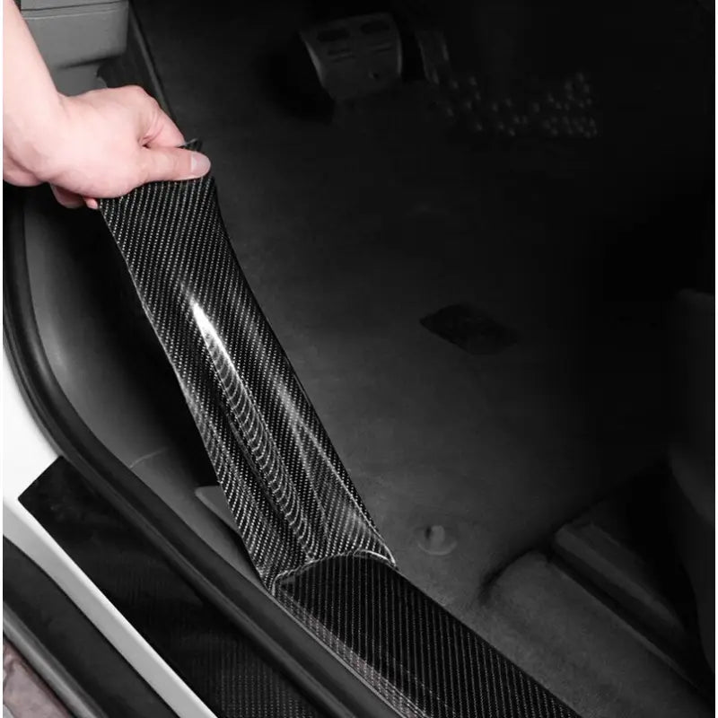 a person holding a piece of carbon fiber in their car
