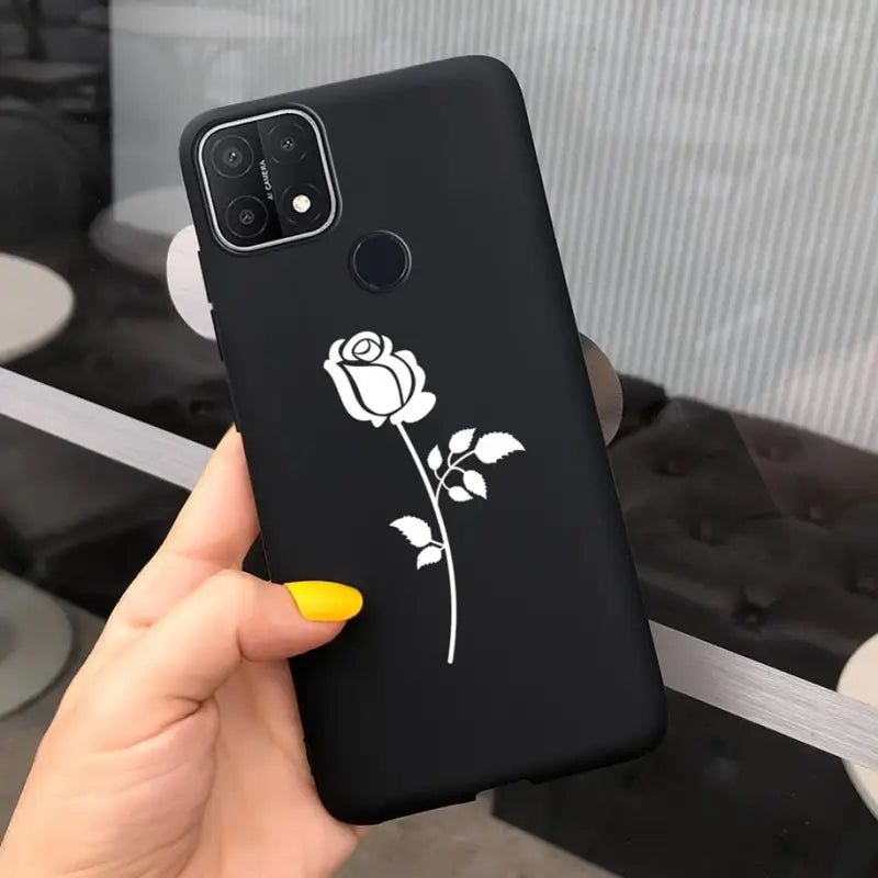 a woman holding a black phone case with a white rose on it