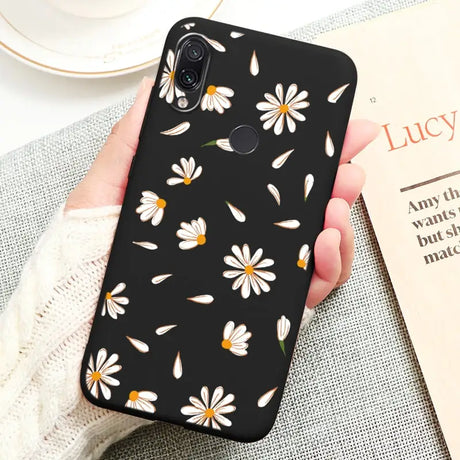 a person holding a black phone case with white daisies on it