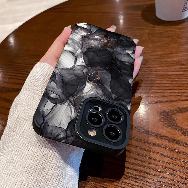 a woman holding a black and white marble phone case
