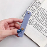 a hand holding a bookmark over a book