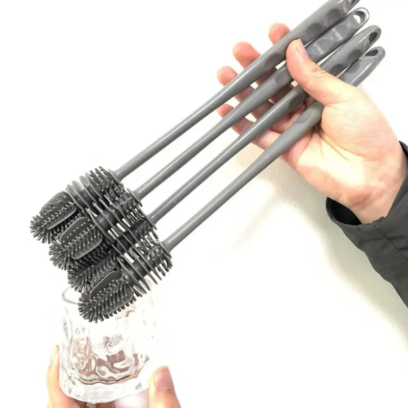a hand holding a bottle with a black and gray plastic brush