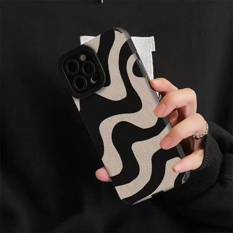 a person holding a phone case with a black and white pattern