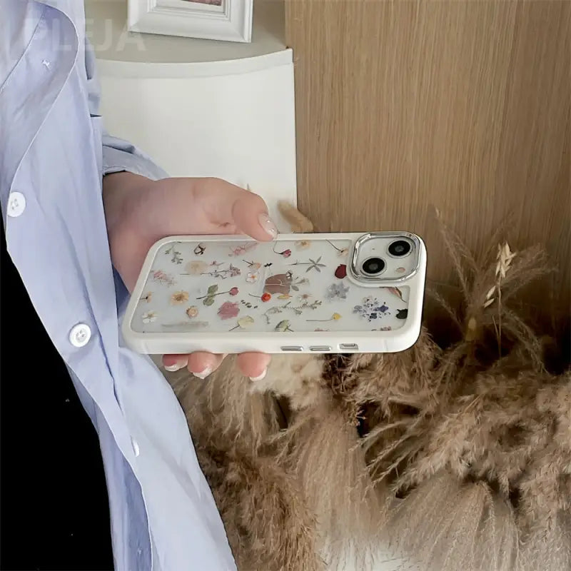a person holding a phone with a cat in the background