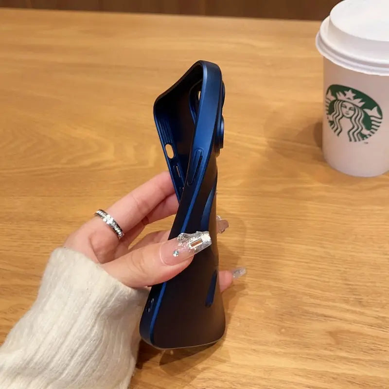 someone holding a blue phone in their hand near a cup of coffee