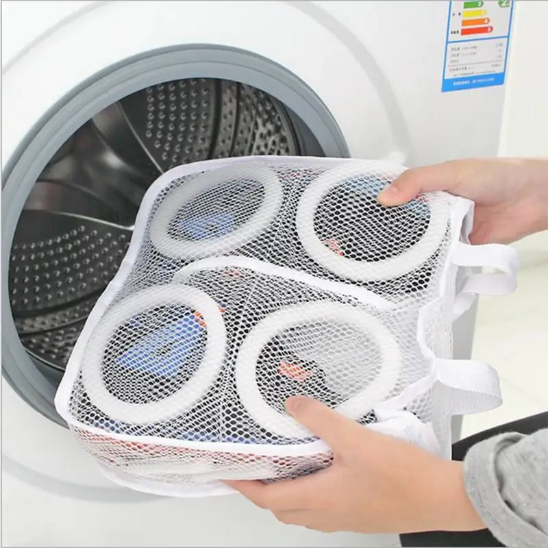 a person holding a mesh bag over a washing machine
