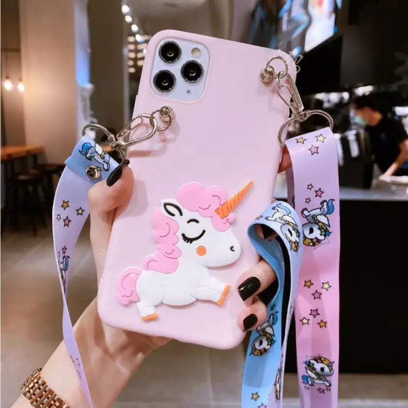 a woman holding a pink phone case with a unicorn on it