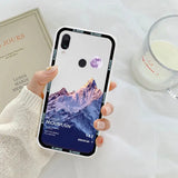 a woman holding a phone case with a mountain scene on it