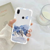 a woman holding a phone case with a mountain scene