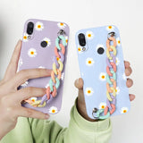 a woman holding up two phone cases with flowers on them