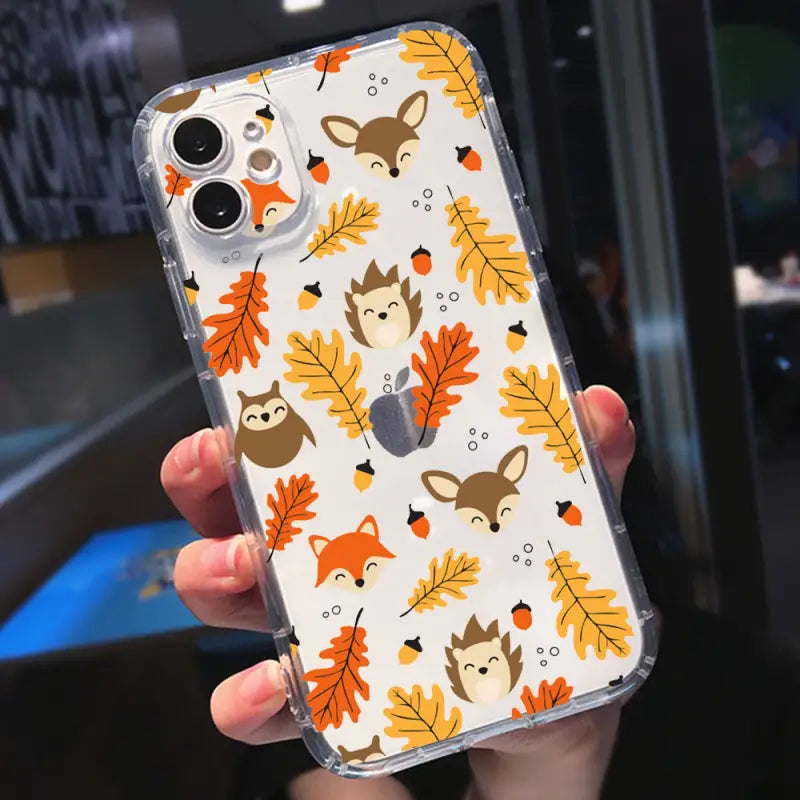 a person holding a phone case with a pattern of leaves and animals