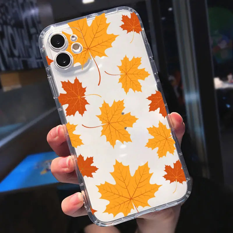 a person holding a phone case with a pattern of orange leaves