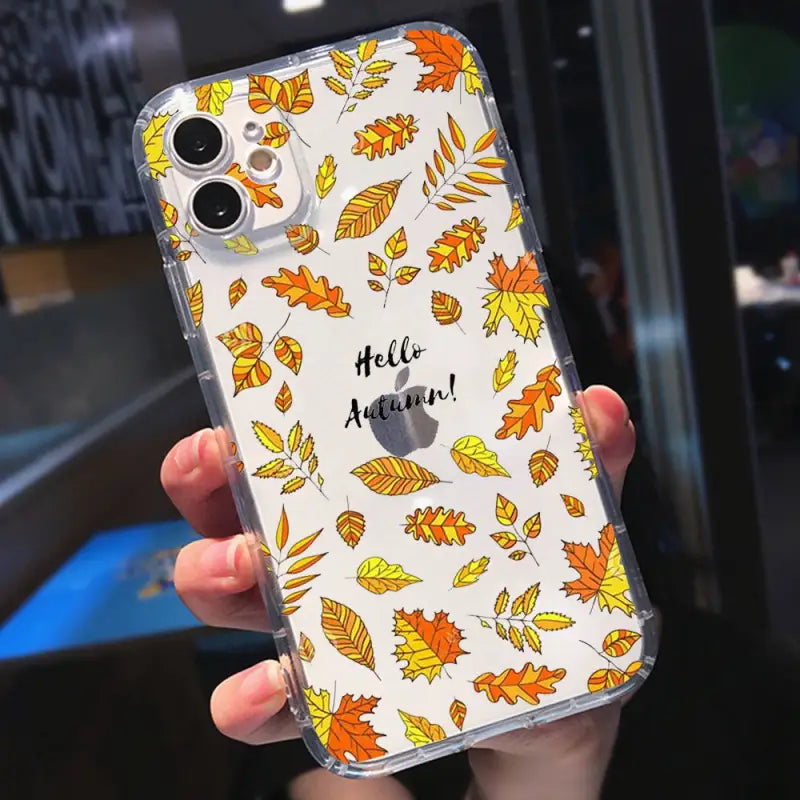 a person holding a phone case with autumn leaves