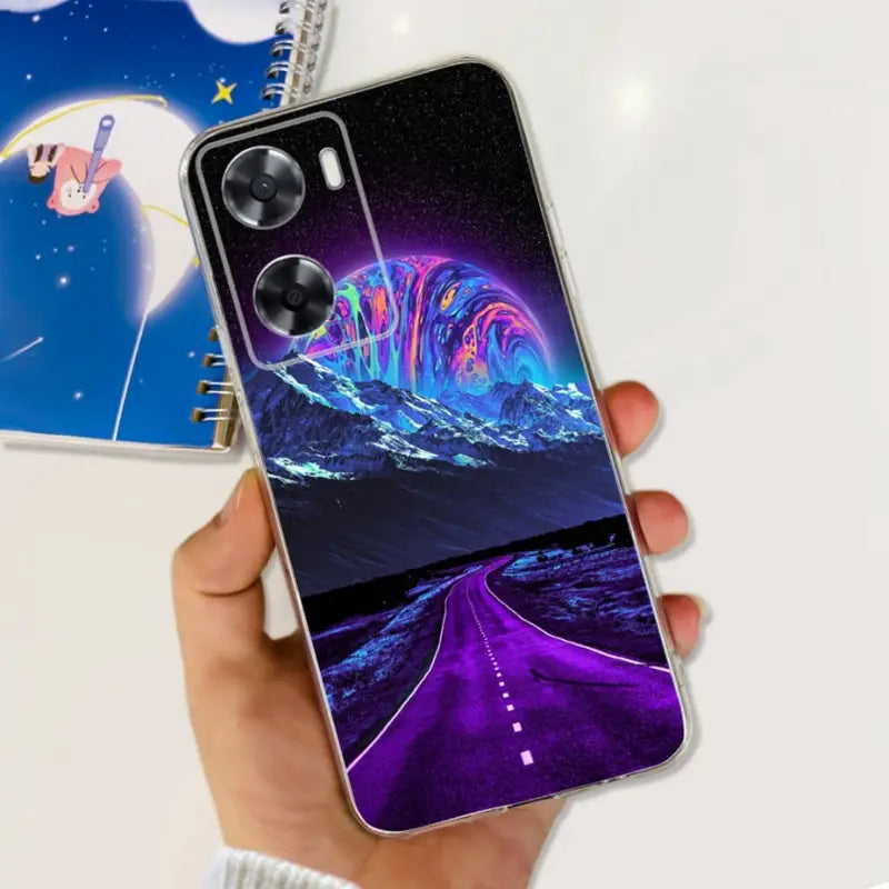 a hand holding a phone case with a purple and blue galaxy landscape