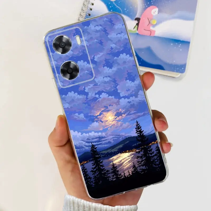 a person holding a phone case with a painting of a sunset